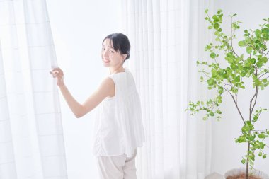 Parlak bir pencereden derin bir nefes alan bir kadın.