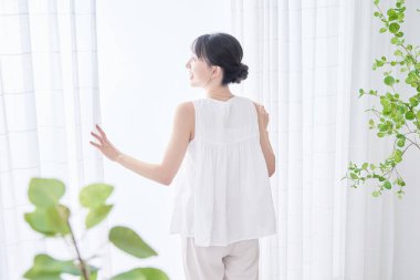 Parlak bir pencereden derin bir nefes alan bir kadın.