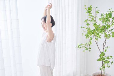 Parlak bir pencereden derin bir nefes alan bir kadın.