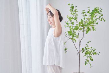 Parlak bir pencereden derin bir nefes alan bir kadın.