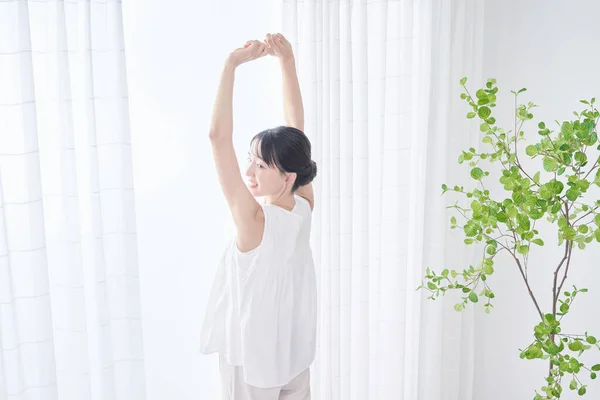 A woman taking a deep breath by a bright window