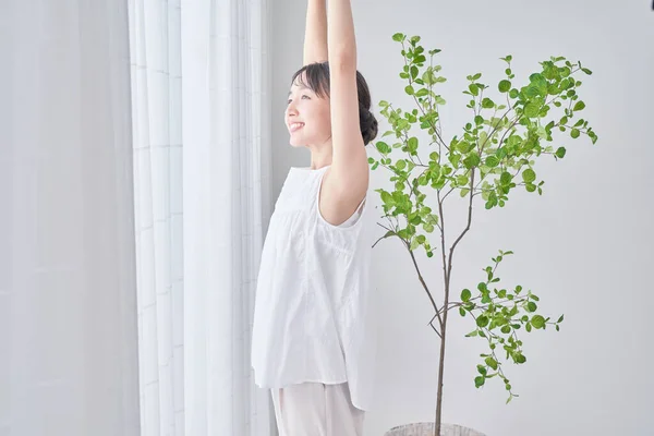 A woman taking a deep breath by a bright window