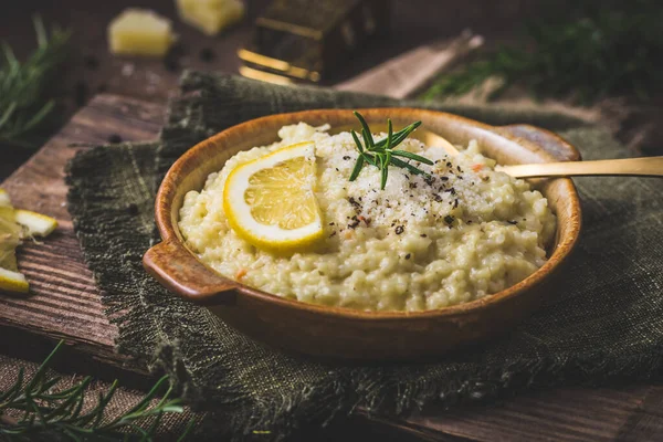 Lemon rice risotto with rosemary on dark wooden background