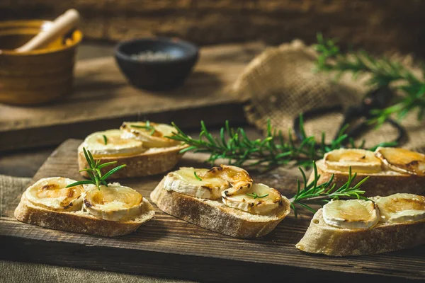 ヤギチーズと蜂蜜で焼いたバゲットパンのスライスは ローズマリーで飾られています — ストック写真