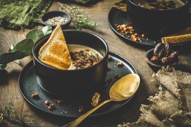 Gül soslu kestane çorbası, krema ve ekmek kırsal ahşap arka planda siyah bir kasede