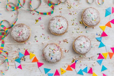 Krapfen, Berliner ya da beyaz ahşap arka planda flama, konfeti ve mini marşmelovlu çörekler. Renkli karnaval ya da doğum günü resmi, üst görünüm