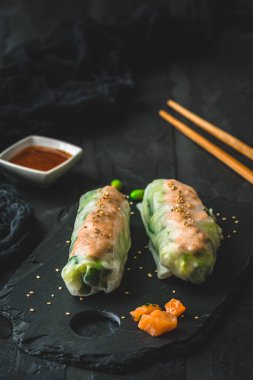 Siyah arka planda salata ve somon ile iki yaz rulosu, Japon, Asya yemekleri, dikey