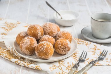 Beyaz ahşap arka planda şekerli kızarmış kaymak topları. Kahve molası kavramı. Boşluğu kopyala.
