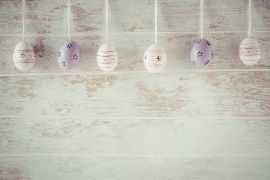Beyaz ahşap bir duvarın önünde pembe, beyaz ve mor Paskalya yumurtaları, klasik tarz, kopyalama alanı