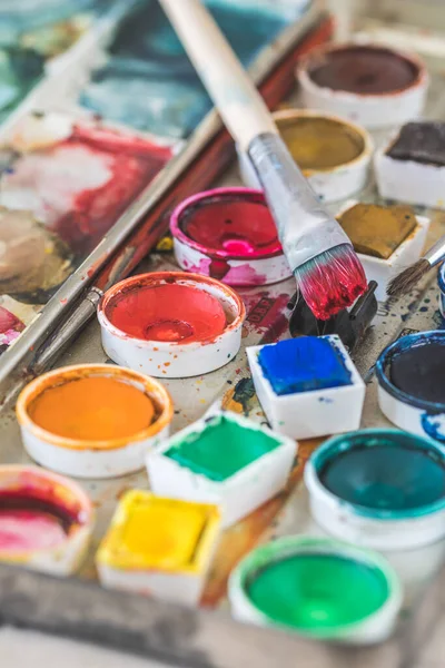 Renkli suluboya boyalı eski boya kutusu, kırmızı boyalı fırça. Dikey.