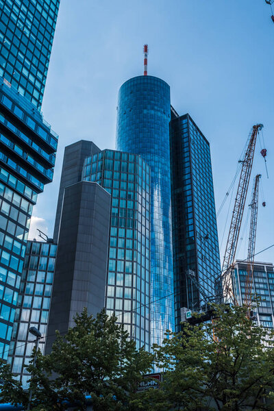 Modern business buildings, skyscrapers with glass facades in Frankfurt am Main. On the right, construction cranes, where more high-rise buildings are being built