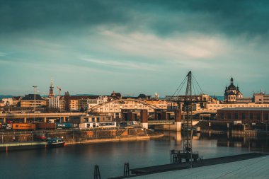 Mannheim, Almanya - 26.03.2021: Sanayi, konut binaları ve alacakaranlıktaki Cizvit Kilisesi manzaralı liman bölgesi