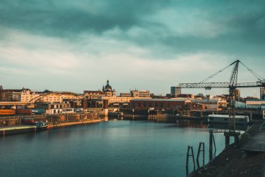 Mannheim, Almanya - 26.03.2021: Sanayi, konut binaları ve alacakaranlıktaki Cizvit Kilisesi manzaralı liman bölgesi