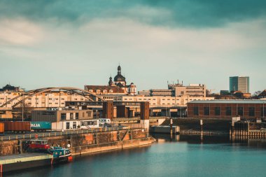 Mannheim, Almanya - 26.03.2021: Endüstri, konut binaları ve güzel akşam ışığında Cizvit Kilisesi manzaralı liman bölgesi