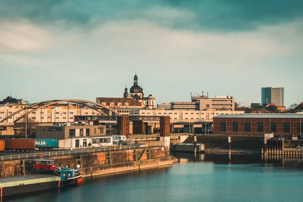 Mannheim, Almanya - 26.03.2021: Endüstri, konut binaları ve güzel akşam ışığında Cizvit Kilisesi manzaralı liman bölgesi