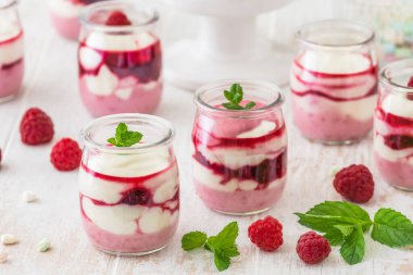 Fruity quark dessert with raspberries and chocolate or crisp topping in small glasses