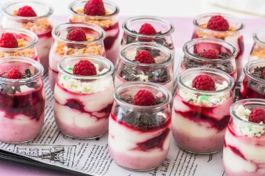 Fruity quark dessert with raspberries and chocolate or crisp topping in small glasses