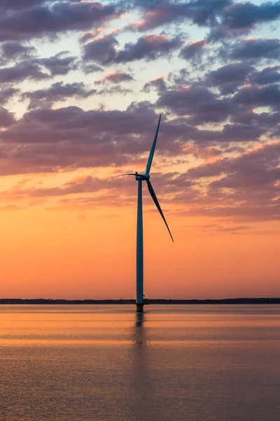 Wind turbine in the sea in the warm sunset light, vertical