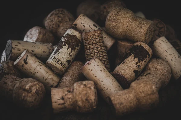 Two corks on a pile of used corks which show a world map and the word friendly. Dark background. Concept of better world.