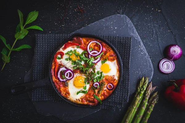 鉄鍋の中のしゃっくり 中東の伝統料理 トマトと目玉焼き ピーマン 野菜やハーブ 卵の上に日当たりの良い側 トップ表示 — ストック写真