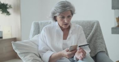 Mutlu yaşlı kadın müşteri elinde bankacılık kredi kartı tutuyor ve mal alıyor..