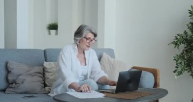 Olgun iş kadını, ticaret bilgileri ve yatırım kar sonuçlarıyla birlikte dizüstü bilgisayar ve mali tabaka kullanıyor.