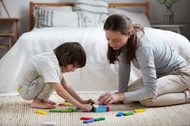 Kadın bebek bakıcısı ve akıllı çocuk ahşap renkli bloklar eğitim geliştirme oyunu inşa ediyorlar