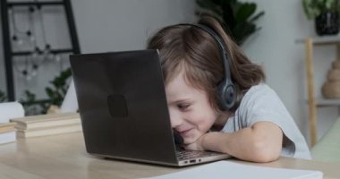 Kulaklık takan küçük bir çocuk internetten bilgisayar yoluyla öğreniyor, ama konsantre olamıyor, şımartıyor..