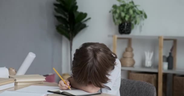 Yorgun okul çocuğu ev ödevinden ve öğrenmekten yoruldu ve masanın üzerinde yatıyor.. — Stok video