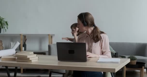 Jonge vrouw freelancer werken op afstand met behulp van laptop van huis en vragen zoon niet te storen — Stockvideo