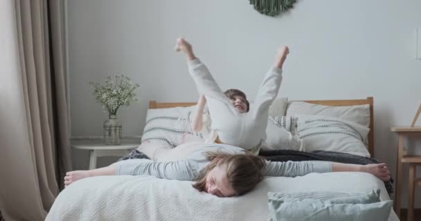 Ridere giovane mamma ingannare giocare con bambino carino figlio sdraiato saltando sul comodo letto in camera da letto — Video Stock