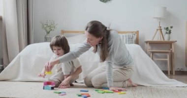 Kadın bebek bakıcısı ve akıllı çocuk ahşap renkli bloklar eğitim geliştirme oyunu inşa ediyorlar