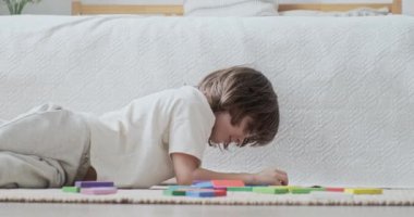Gülümseyen çocuk renkli ahşap tuğlalarla mimari yapmaya odaklanmış oyuncaklar geliştiriyor.