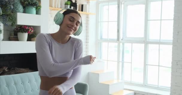 행복 한 젊은 여성 이 혼자 집에서 춤을 추고 음악을 듣기 위해 스마트폰을 사용하는 모습 — 비디오