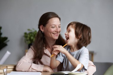 Anne ve tatlı oğul gülüyor ve eğleniyorlar öğrenirken ve evde eğitim alırken..