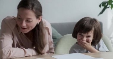Anne ve tatlı oğul gülüyor ve eğleniyorlar öğrenirken ve evde eğitim alırken..