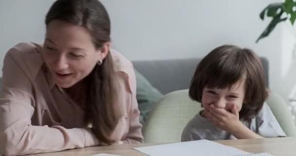 Mãe e filho bonito estão rindo e tendo um tempo feliz enquanto aprende e homeschooling. — Vídeo de Stock