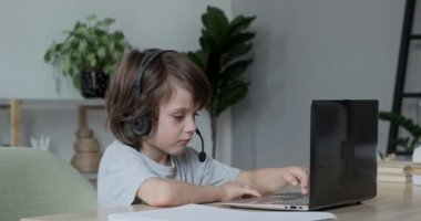 Ciddi odaklı anaokulu öğrencisi internette görüntülü sohbet laptopuyla öğreniyor. Bilgisayar okuyan çocuk
