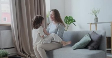 Keyifli, neşeli, heyecanlı oğul koşuyor, oynuyor, zıplıyor ve kanepeye yaslanmış genç anneye sarılıyor..