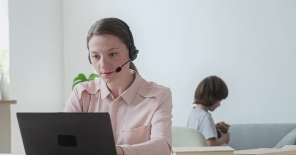 Young female tutor wearing headset teaching students online in video conference. — Stock Video