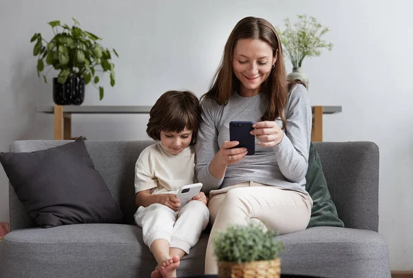 Smějící se žena psaní textové zprávy na telefonu kluk hraje online internet hry smartphone — Stock fotografie