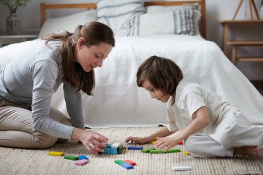Kadın bebek bakıcısı ve akıllı çocuk ahşap renkli bloklar eğitim geliştirme oyunu inşa ediyorlar