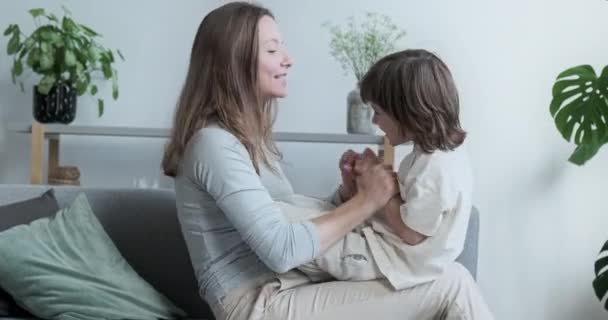 Schöne junge, fröhliche Mutter spielt aktiv mit ihrem entzückenden Sohn im Vorschulalter und kuschelt — Stockvideo