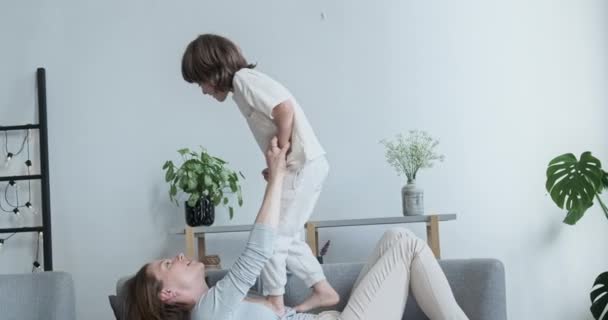 Vorschulkind hat Spaß mit Mutter, hüpft herum und googelt herum. Sein lustiger Tag in der Wohnung — Stockvideo