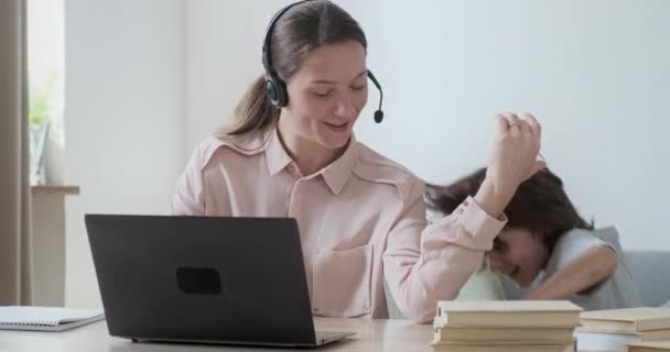 Młoda, skupiona kobieta pracująca zdalnie na laptopie i rozmawiająca z kolegami. — Wideo stockowe
