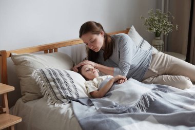 Yakın plan, şefkatli bir anne sıcak alnına dokunup vücut ısısını ölçüyor.