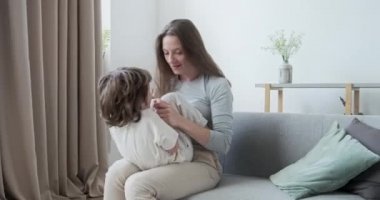 Kaygısız, neşeli, neşeli oğlan çocuğu. Eğlencesine zıplıyor ve genç anneye sarılıyor. Kanepede yatıyor..