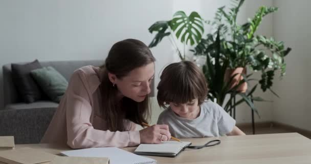 En lycklig mamma visar och berättar för sin son hur man löser ett svårt matematiskt exempel och lär sig räkna och multiplicera. — Stockvideo