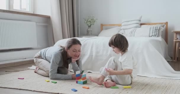 Focalizzato mamma insegnare figlio bambino costruendo mattoni blocchi di architettura in legno in camera da letto — Video Stock