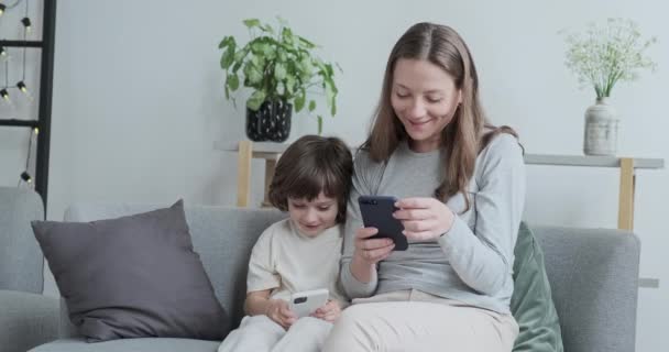 Smějící se žena psaní textové zprávy na telefonu kluk hraje online internet hry smartphone — Stock video